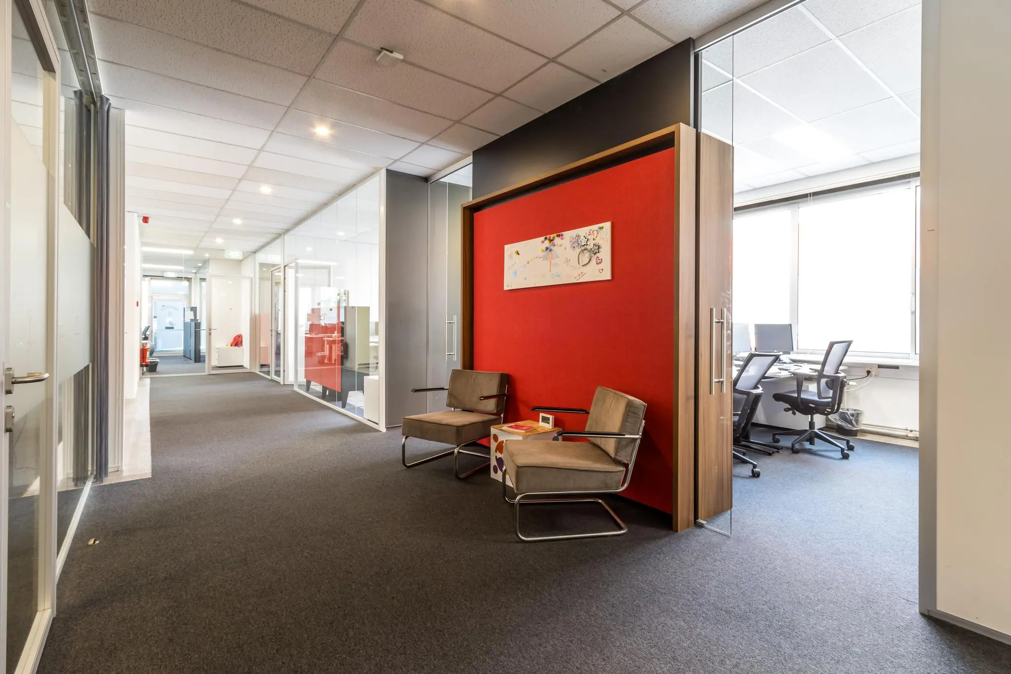 Moderne kantoorruimte aan de Jan van Eycklaan met glazen wanden, zitgedeelte en zicht op werkplekken.